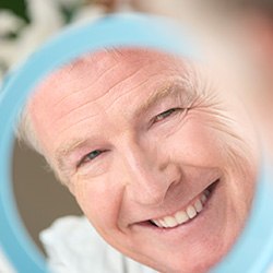 Senior man looking at smile in mirror